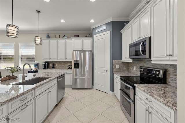 kitchen with appliances with stainless steel finishes, ornamental molding, sink, pendant lighting, and white cabinetry