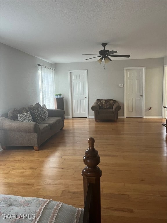 living room with ceiling fan, hardwood / wood-style flooring, and a textured ceiling