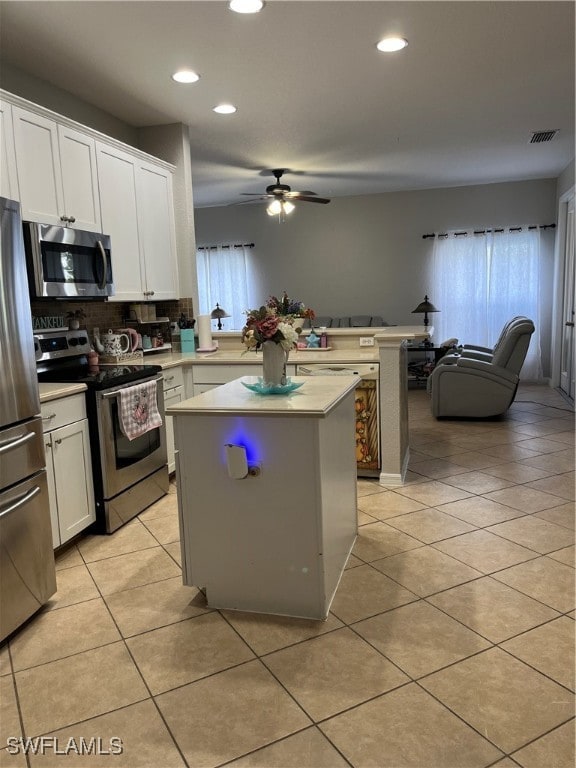 kitchen featuring a wealth of natural light, a kitchen island, appliances with stainless steel finishes, and white cabinets