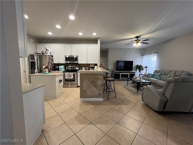 kitchen with decorative backsplash, appliances with stainless steel finishes, a breakfast bar, white cabinetry, and a center island