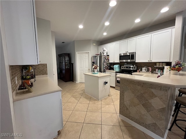 kitchen featuring appliances with stainless steel finishes, a breakfast bar area, a kitchen island, and white cabinets