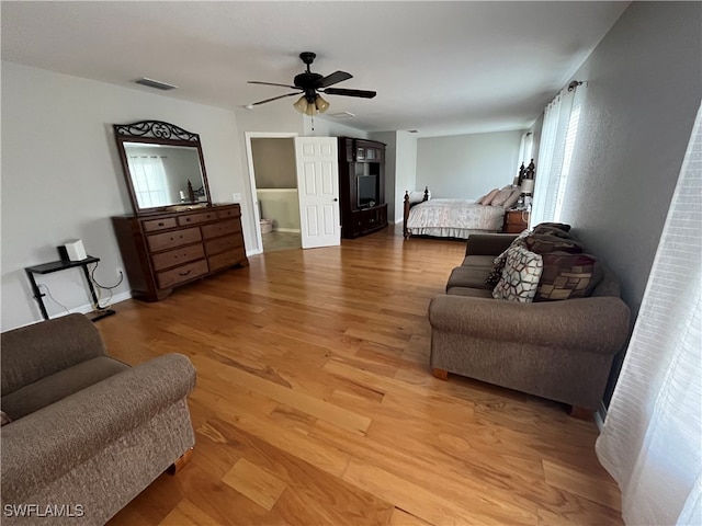 bedroom with ensuite bath, wood-type flooring, and ceiling fan