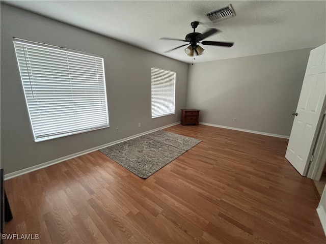 unfurnished bedroom with a textured ceiling, wood-type flooring, and ceiling fan