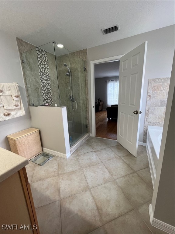 bathroom with vanity, plus walk in shower, a textured ceiling, and tile patterned flooring