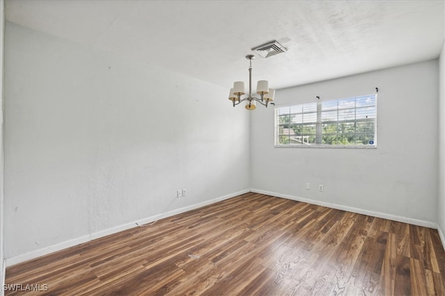 unfurnished room with a notable chandelier and dark hardwood / wood-style floors