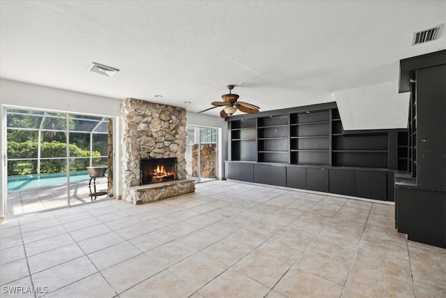 unfurnished living room with a textured ceiling, a fireplace, light tile patterned floors, built in features, and ceiling fan