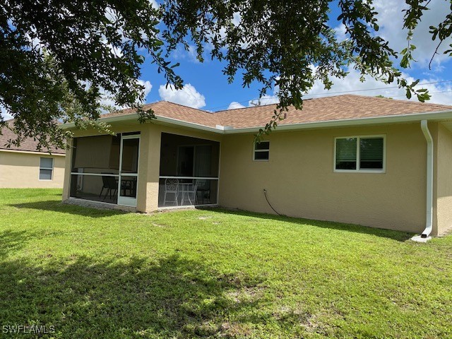 rear view of property featuring a sunroom and a yard