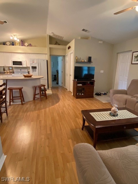 living room featuring ceiling fan, light wood-type flooring, and vaulted ceiling