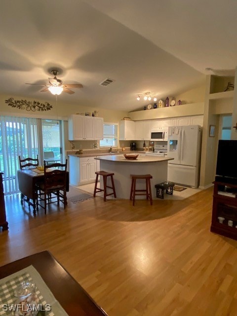 kitchen featuring white cabinets, white appliances, plenty of natural light, and vaulted ceiling