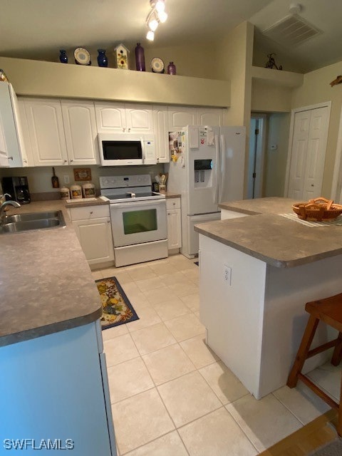 kitchen with light tile patterned flooring, white cabinetry, sink, white appliances, and lofted ceiling