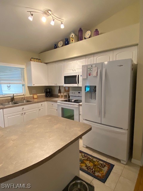 kitchen with white cabinetry, sink, light tile patterned floors, white appliances, and vaulted ceiling