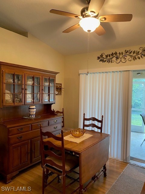 dining room with ceiling fan, light wood-type flooring, and vaulted ceiling