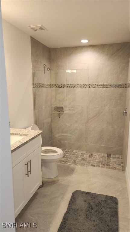 bathroom with vanity, toilet, and tiled shower