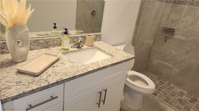 bathroom featuring vanity, toilet, and tiled shower