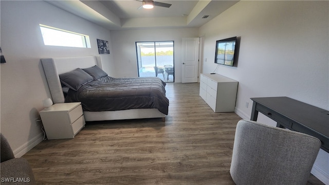 bedroom featuring a raised ceiling, hardwood / wood-style flooring, ceiling fan, and access to outside