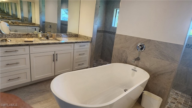 bathroom with tile walls, separate shower and tub, and vanity