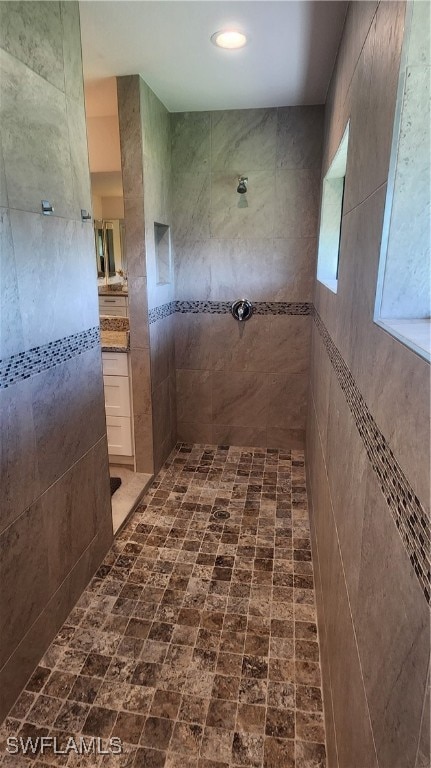 bathroom with tiled shower and vanity