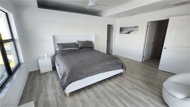 bedroom featuring light hardwood / wood-style flooring, ceiling fan, and a tray ceiling