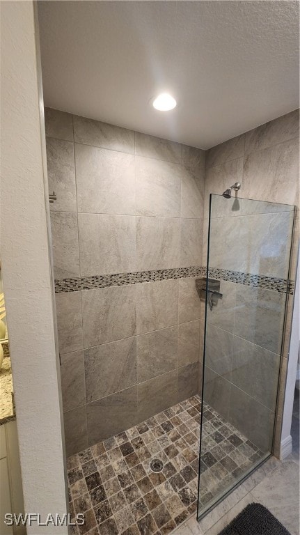 bathroom with tiled shower and vanity