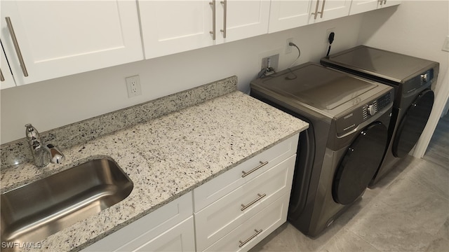 clothes washing area with independent washer and dryer, cabinets, and sink