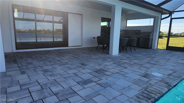 view of patio with glass enclosure and area for grilling