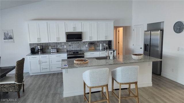 kitchen featuring a center island with sink, stainless steel appliances, sink, and white cabinetry