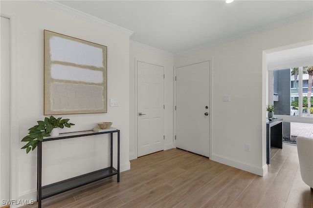 foyer with light wood-type flooring and crown molding