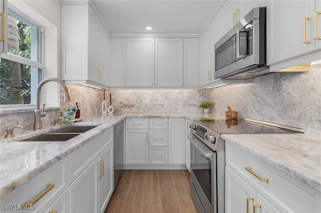 kitchen with stainless steel appliances, backsplash, sink, and white cabinetry