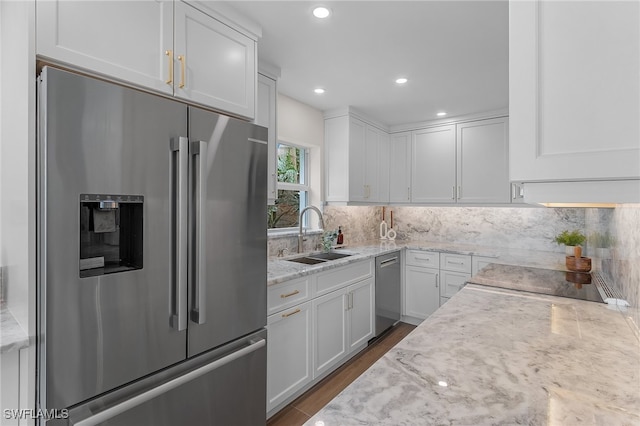 kitchen featuring light stone counters, stainless steel appliances, sink, and white cabinetry