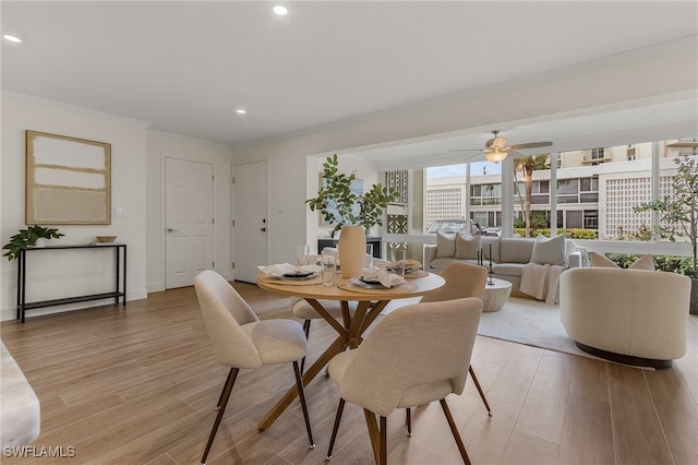 dining area with ceiling fan, light wood-type flooring, and ornamental molding