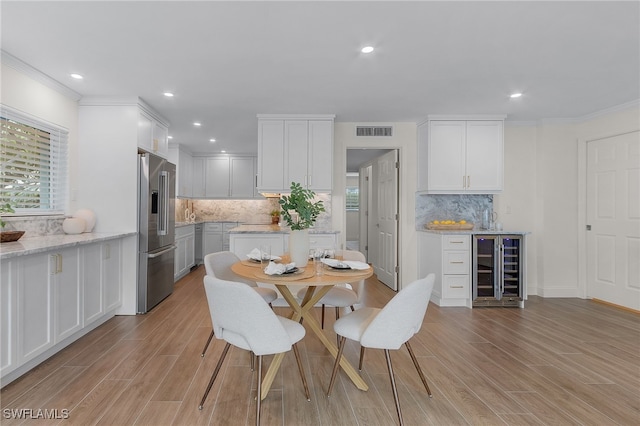 dining area with crown molding, sink, light hardwood / wood-style flooring, and wine cooler