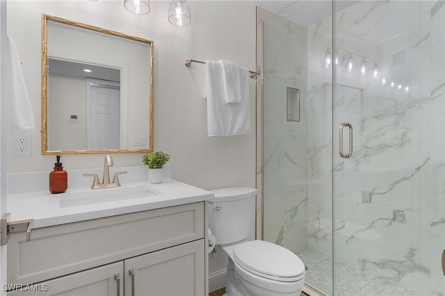 bathroom featuring vanity, a shower with shower door, and toilet