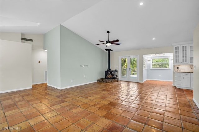 unfurnished living room featuring high vaulted ceiling, a wood stove, and light tile patterned floors