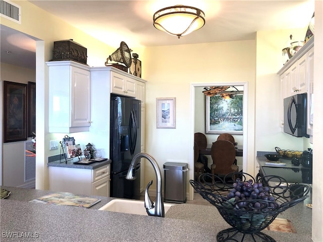 kitchen with black appliances, sink, white cabinets, and carpet