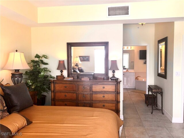 bedroom with ensuite bath, sink, and light tile patterned flooring