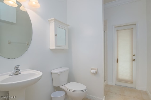 bathroom with a shower with door, toilet, sink, and tile patterned floors