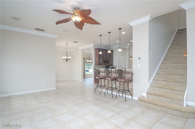 interior space featuring ornamental molding, kitchen peninsula, a kitchen breakfast bar, and ceiling fan with notable chandelier