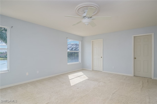 unfurnished room with ceiling fan, plenty of natural light, and light carpet