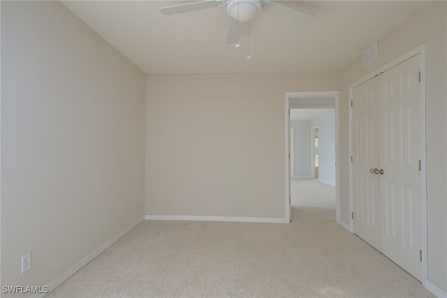 empty room featuring ceiling fan and light colored carpet