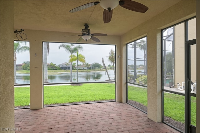 unfurnished sunroom with a water view and ceiling fan