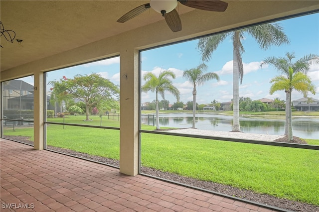 unfurnished sunroom featuring ceiling fan and a water view