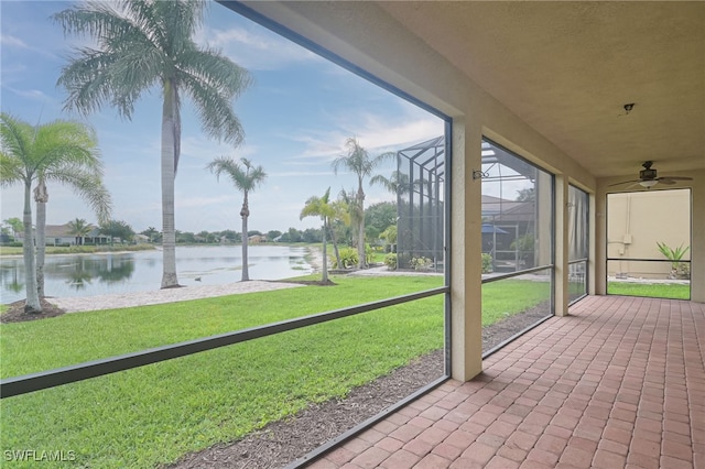 unfurnished sunroom featuring ceiling fan and a water view