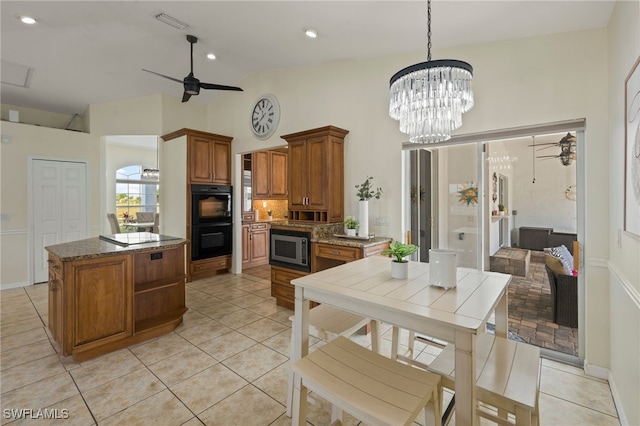 kitchen with stainless steel microwave, lofted ceiling, ceiling fan with notable chandelier, hanging light fixtures, and double oven