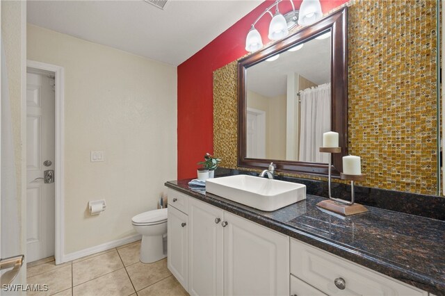 bathroom with toilet, vanity, and tile patterned floors