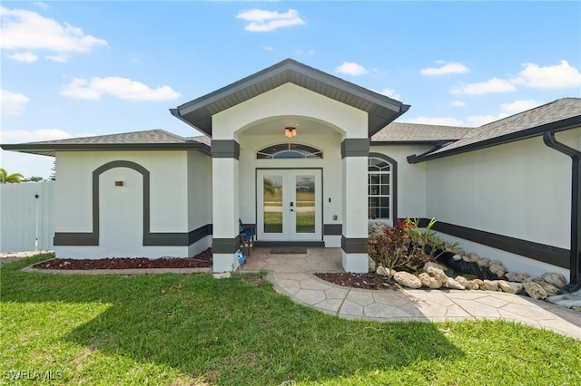 view of exterior entry featuring a lawn and french doors