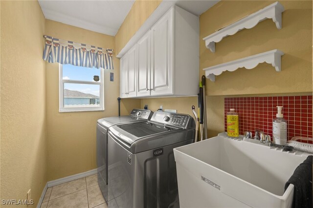 laundry area featuring separate washer and dryer, sink, light tile patterned flooring, and cabinets