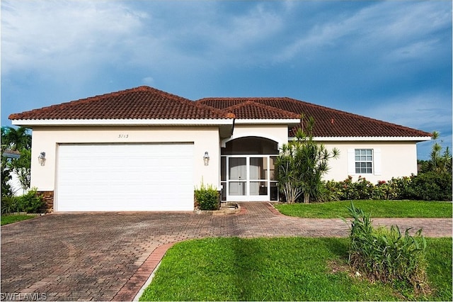 mediterranean / spanish house featuring a garage and a front lawn