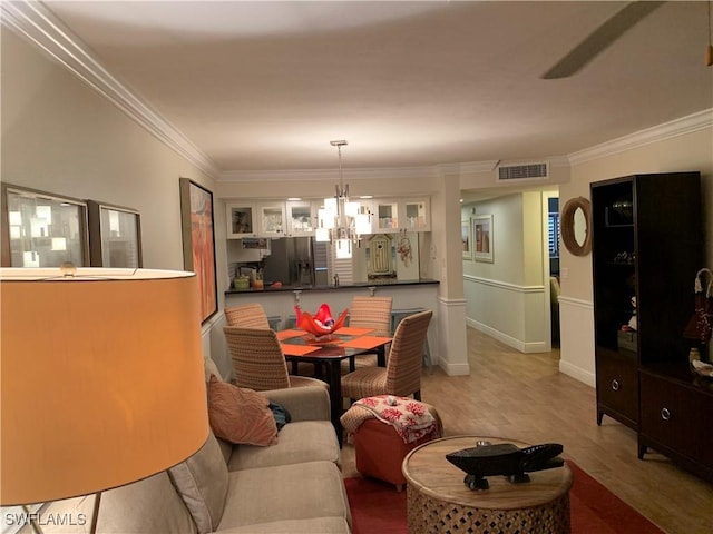 dining room featuring a notable chandelier, light wood-type flooring, and ornamental molding