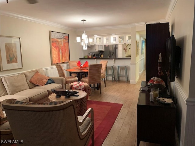 living room featuring light wood-type flooring, crown molding, and a notable chandelier