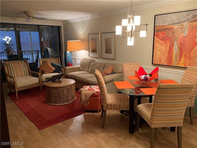 dining room with wood-type flooring, ceiling fan with notable chandelier, and ornamental molding